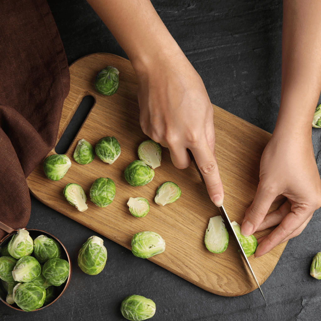 Cutting Brussels Sprouts Salad on a wooden board with a lot of sprouts spread around. 