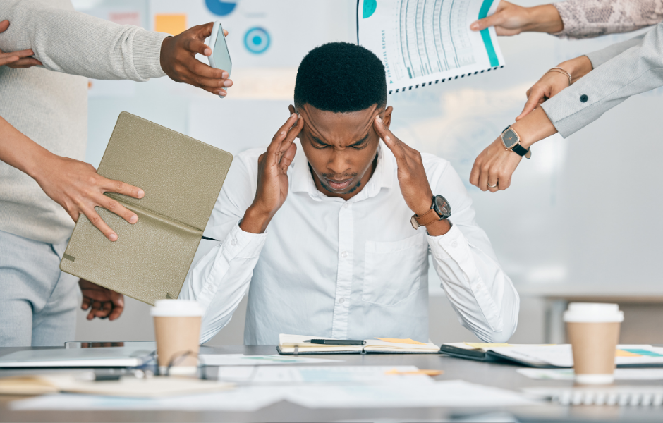 A stressed individual holding their head while surrounded by multiple people demanding attention, symbolizing the impact of stress on gut health and its role in healing leaky gut.