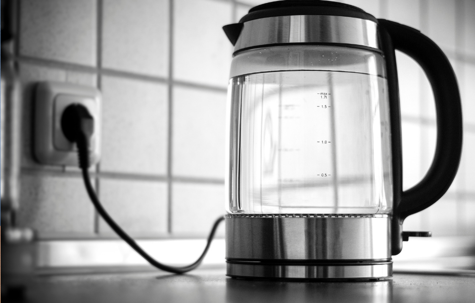 A sleek glass model among the best electric kettles, plugged in and heating water for fast and convenient brewing.