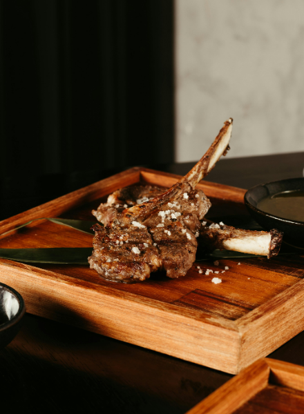 A gourmet lamb chop dish presented on a wooden platter, garnished with coarse salt, showcasing the fine dining experience at one pf hidden gem restaurants DC.