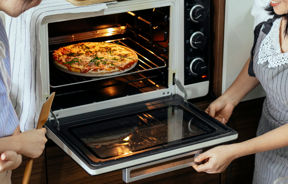 An inviting scene depicting the joy of home cooking while doing  GE Monogram Oven review. The image captures a perfectly baked pizza emerging from the oven, showcasing the precision, convenience, and high performance of this premium kitchen appliance.