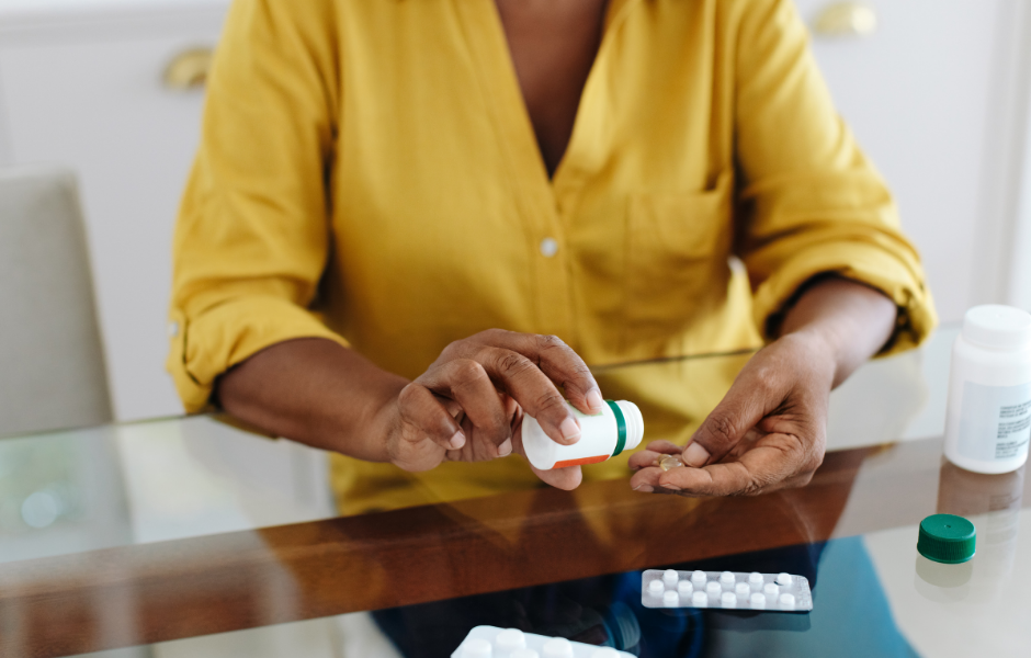 A woman in a yellow shirt pouring pills from a medication bottle, highlighting concerns about lactose in medication.