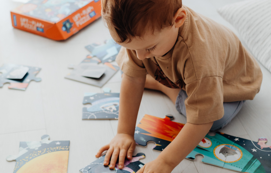 A toddler playing with a puzzle on the floor, an activity that can help prepare for bedtime and support tips on how to put a toddler to sleep