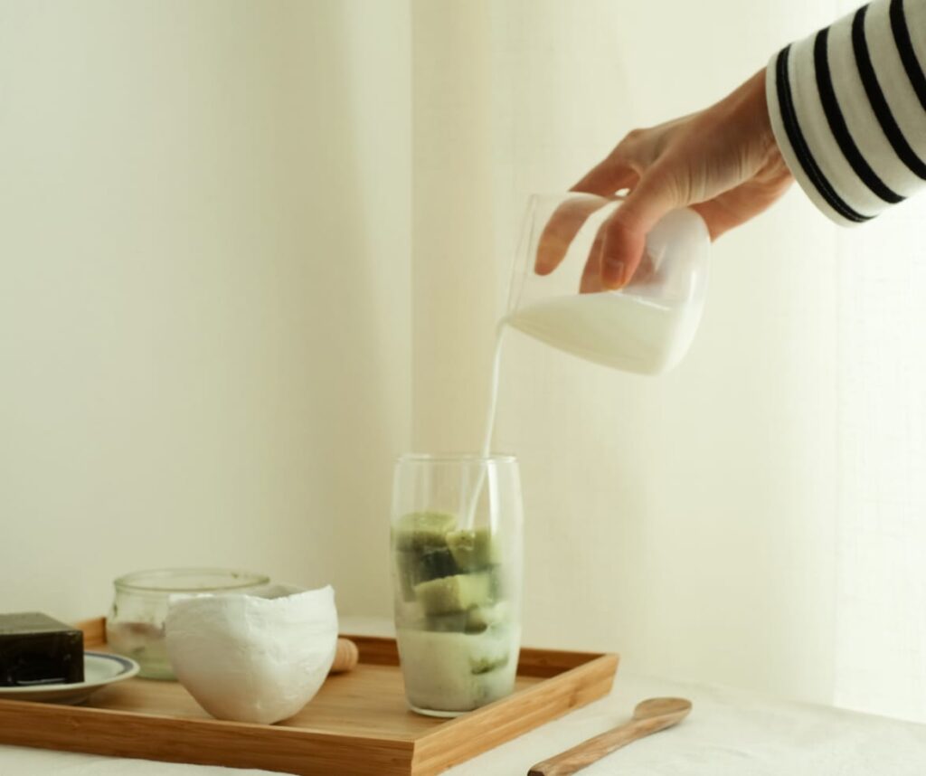 Milk being poured into a glass of matcha ice cubes. The Ultimate Dalgona Matcha Latte Recipe: Boost Your Health and Savor Every Sip.
