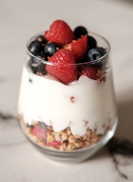 Nourishing Mornings: A glass of yogurt layered with granola, raspberries, and blueberries, highlighting the power of fruits in your breakfast routine.