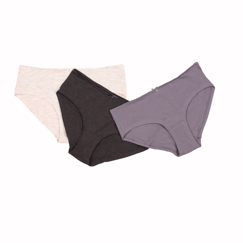 Three pairs of women’s underwear are displayed against a white background. The underwear is neatly arranged with one pair in cream, another in black, and the third in a light purple color. Each pair has a different cut and style, suggesting variety in design for comfort or aesthetic preference. Image used for the article Pregnancy Capsule Wardrobe Essential.