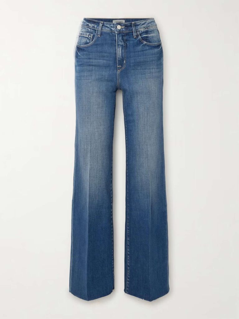 A pair of blue denim jeans with a flared leg design, displayed against a plain background. The jeans feature a faded wash on the thighs and knees, with visible stitching and standard five-pocket styling. The waistband has belt loops and a button closure, emphasizing the classic denim aesthetic, a cool mom outfit in 30s