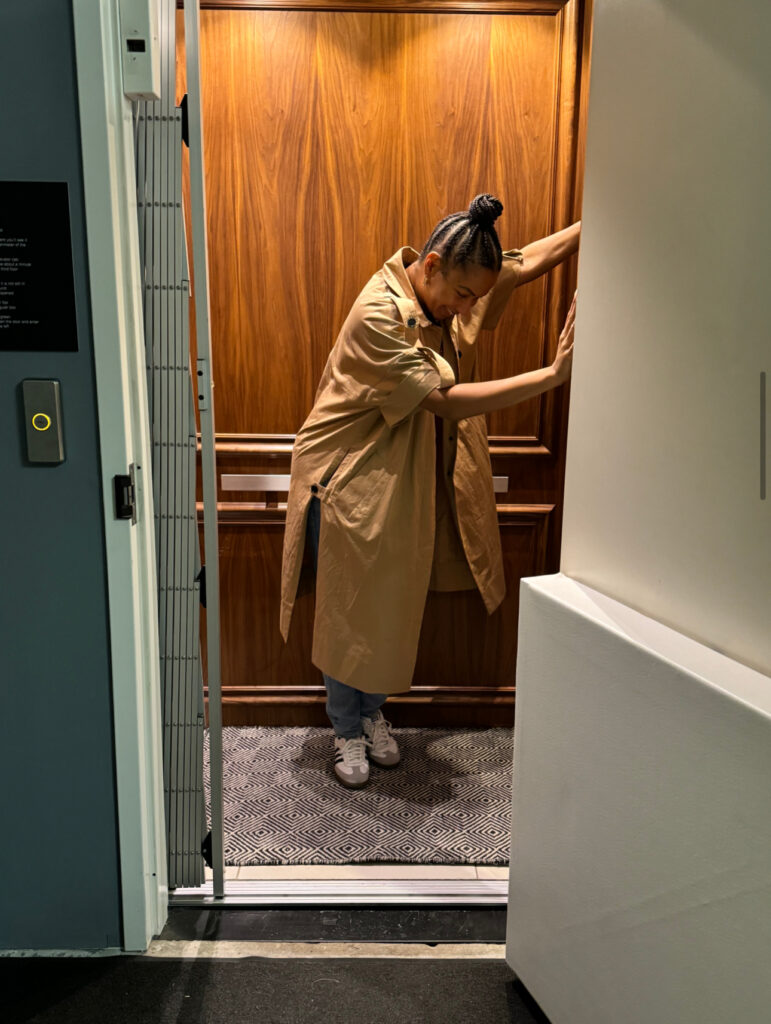 A woman stepping out of a stylish wooden elevator, capturing a moment of exploration during an exciting Asheville adventure.