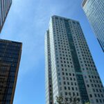 Image of several tall, modern skyscrapers viewed from below, set against a clear blue sky. The buildings feature a mix of glass and concrete facades, reflecting the sunlight. One of the buildings prominently displays the name "PNC" near the top. Trees can be seen in the foreground, adding a touch of greenery to the urban setting. Image used for the article Things to do in Huntsville.