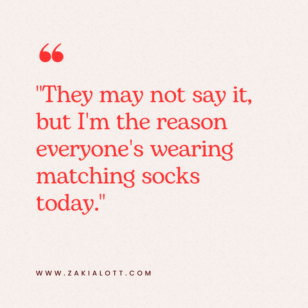 Close-up image of a humorous quote on a light beige background. The text, written in bold red font, says, They may not say it, but I'm the reason everyone's wearing matching socks today. The design exudes a lighthearted and relatable tone.