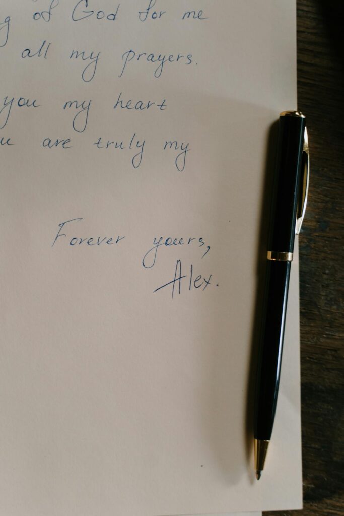 Image of a handwritten note on a piece of paper with a black and gold pen resting beside it. The text on the paper includes phrases expressing deep affection and ends with Forever yours, Alex. The handwriting is neat, and the setting suggests a personal, heartfelt message representing messages of thanks and appreciation.