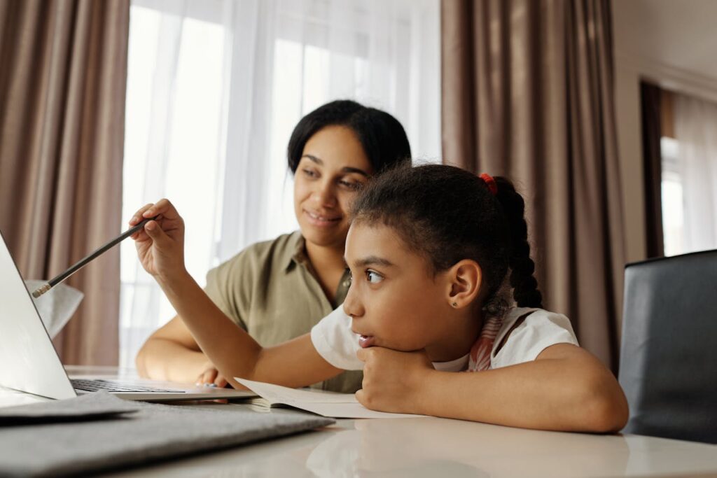 Image of a mother guiding her daughter on a laptop, emphasizing focus and learning in a supportive atmosphere showing What benefits can I claim if I am a stay at home mom.