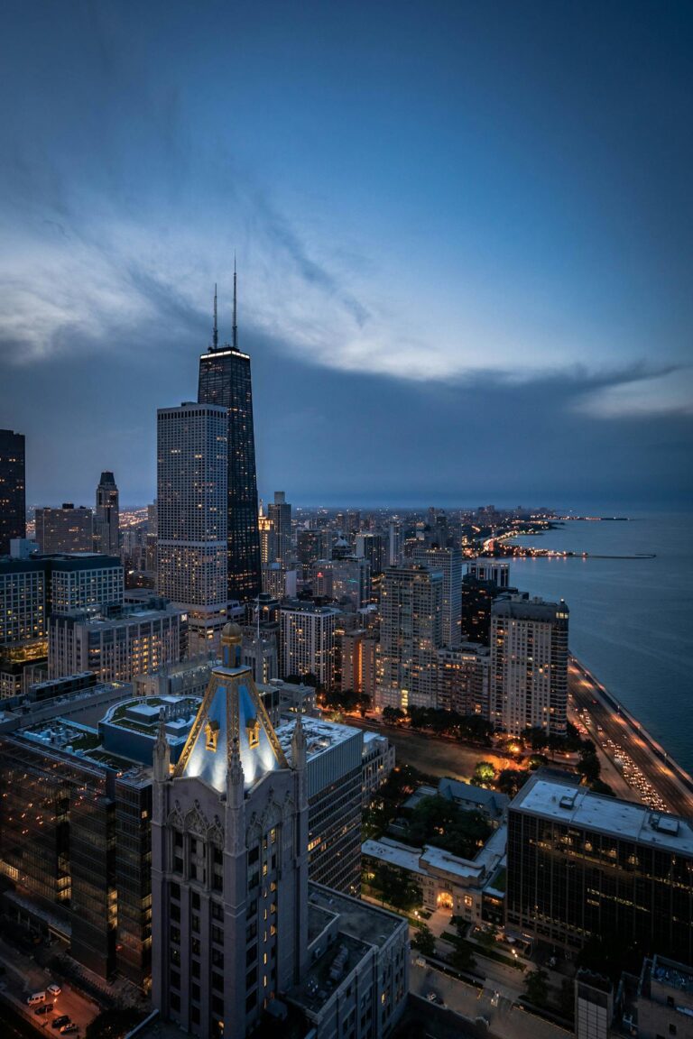 Image of a cityscape of Chicago at dusk, featuring the John Hancock Center and Lake Michigan, showing one day in Houston.