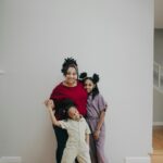 Image of a smiling mother with two daughters, posing together indoors near a staircase showing 10 best states that help single mothers