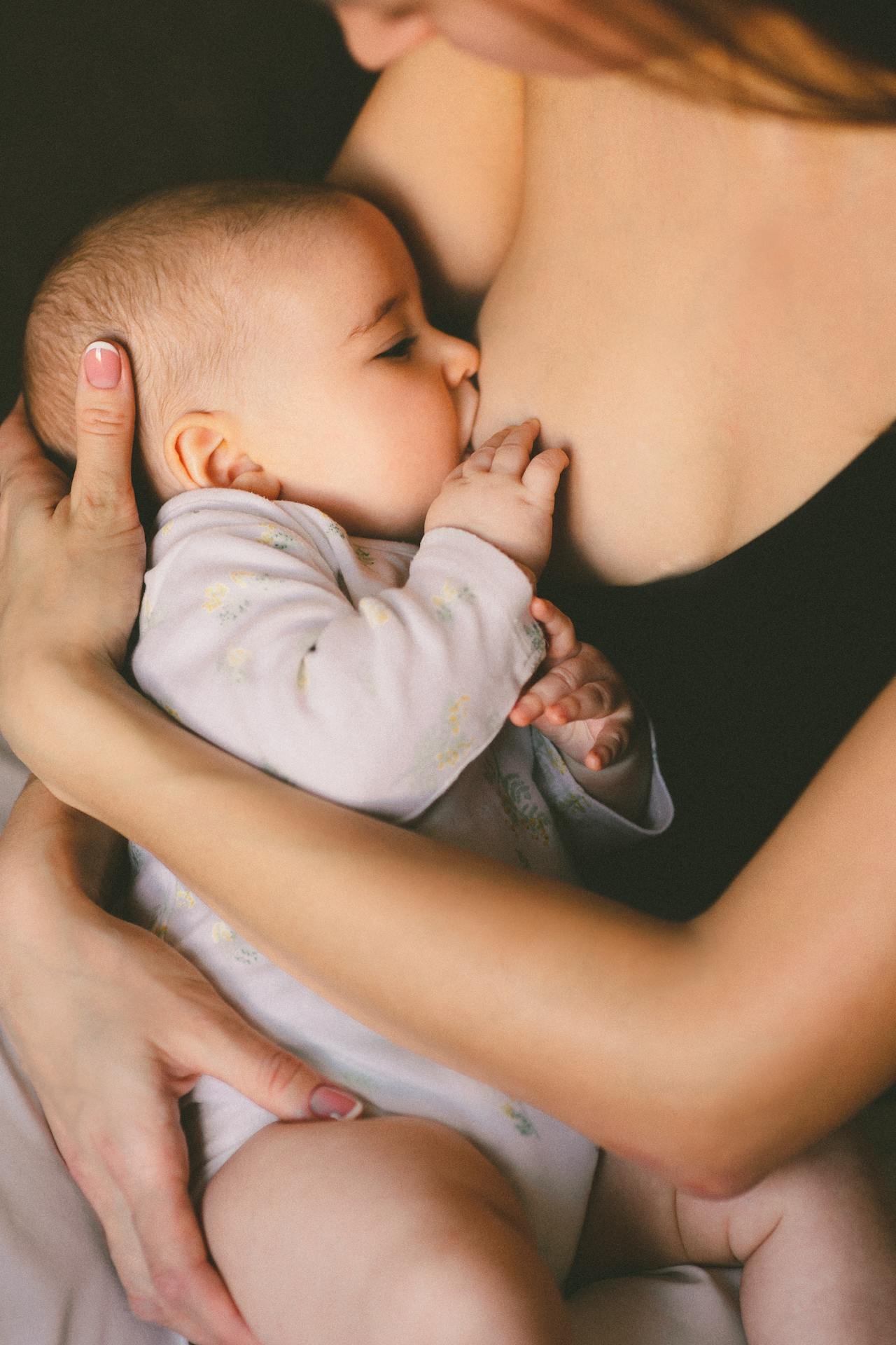 Image of a mother breastfeeding her baby, with close-up focus on the nurturing bond and gentle embrace, showing tips to get rid of colic in breastfed babies.