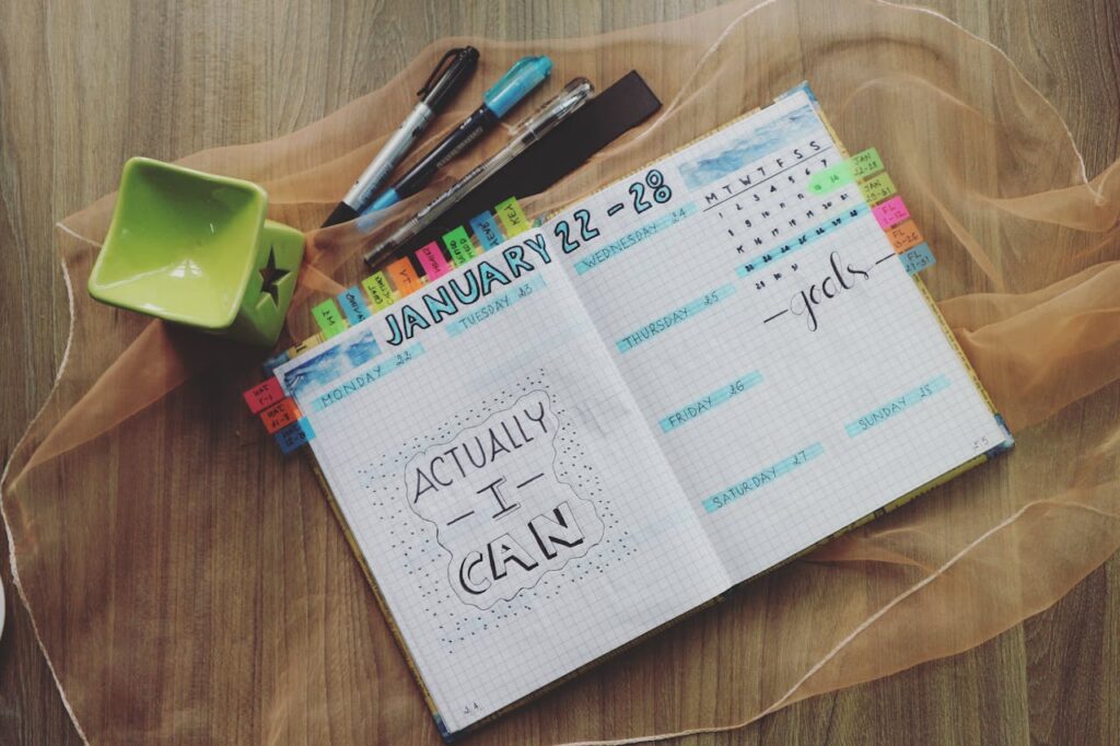 Image of a neatly organized journal displaying a weekly planner with motivational text and colorful tabs showing set a daily and weekly routine.