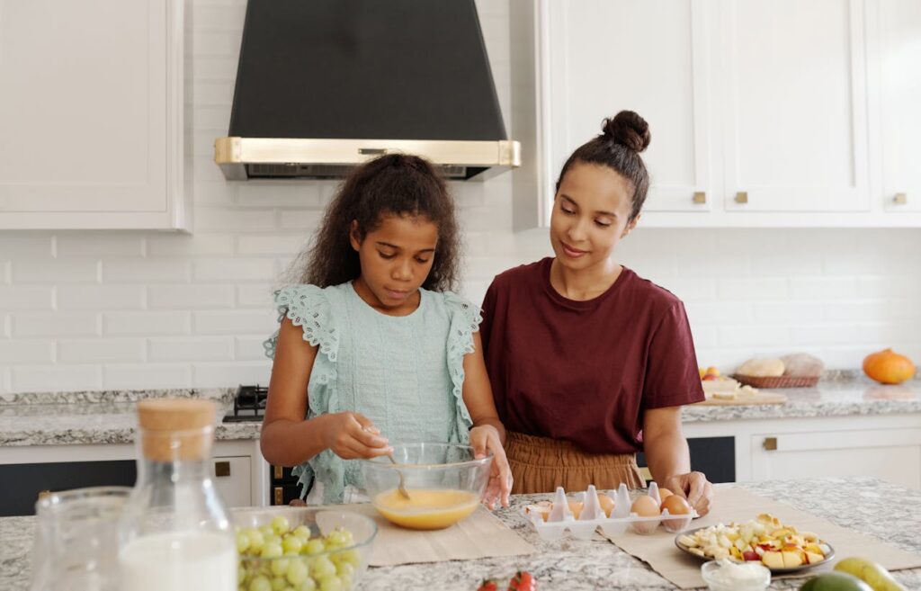 Close-up image of a mother and daughter cooking together in a bright kitchen, mixing ingredients in a bowl, showing stay-at-home mom struggles.