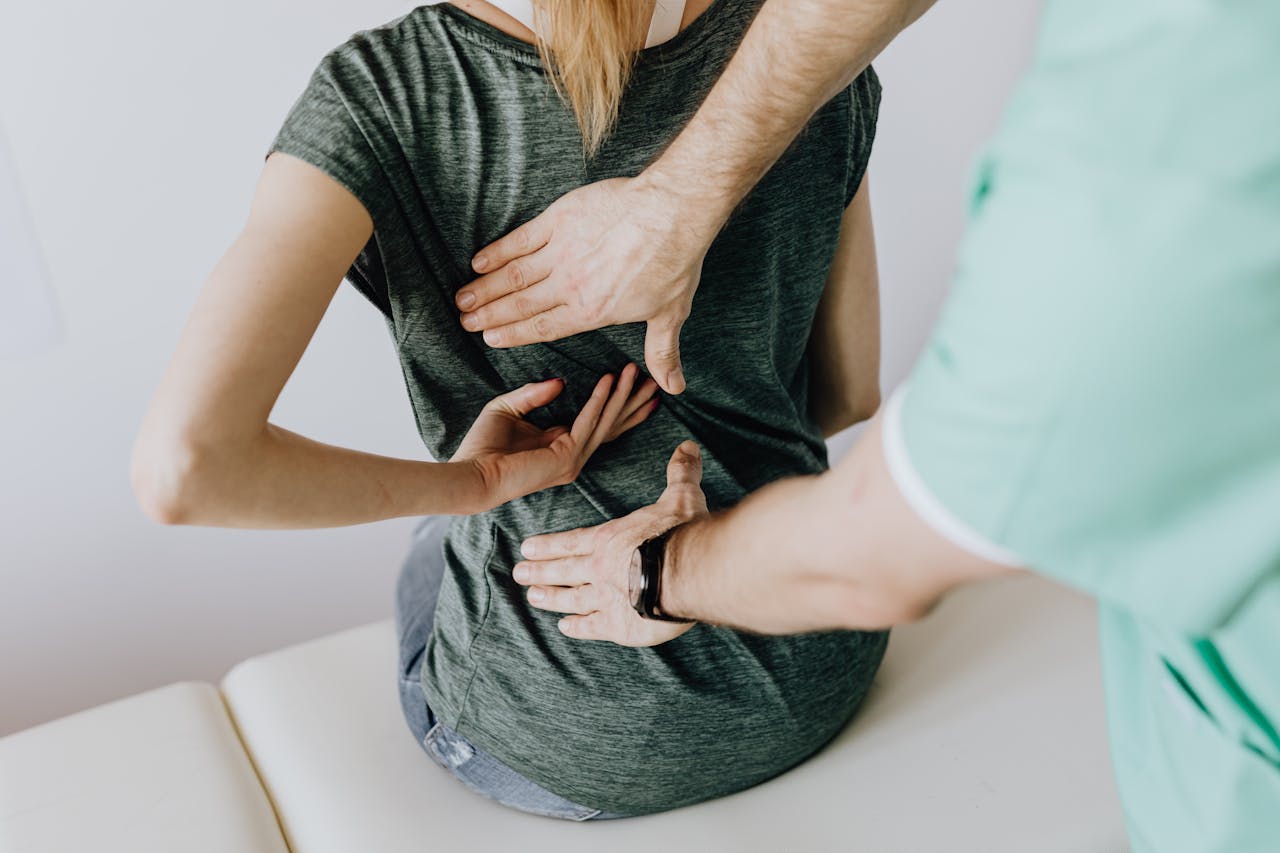 Image of a chiropractor examines a woman's back, guiding her hands for a posture or pain assessment, showing signs your body is preparing for labor.