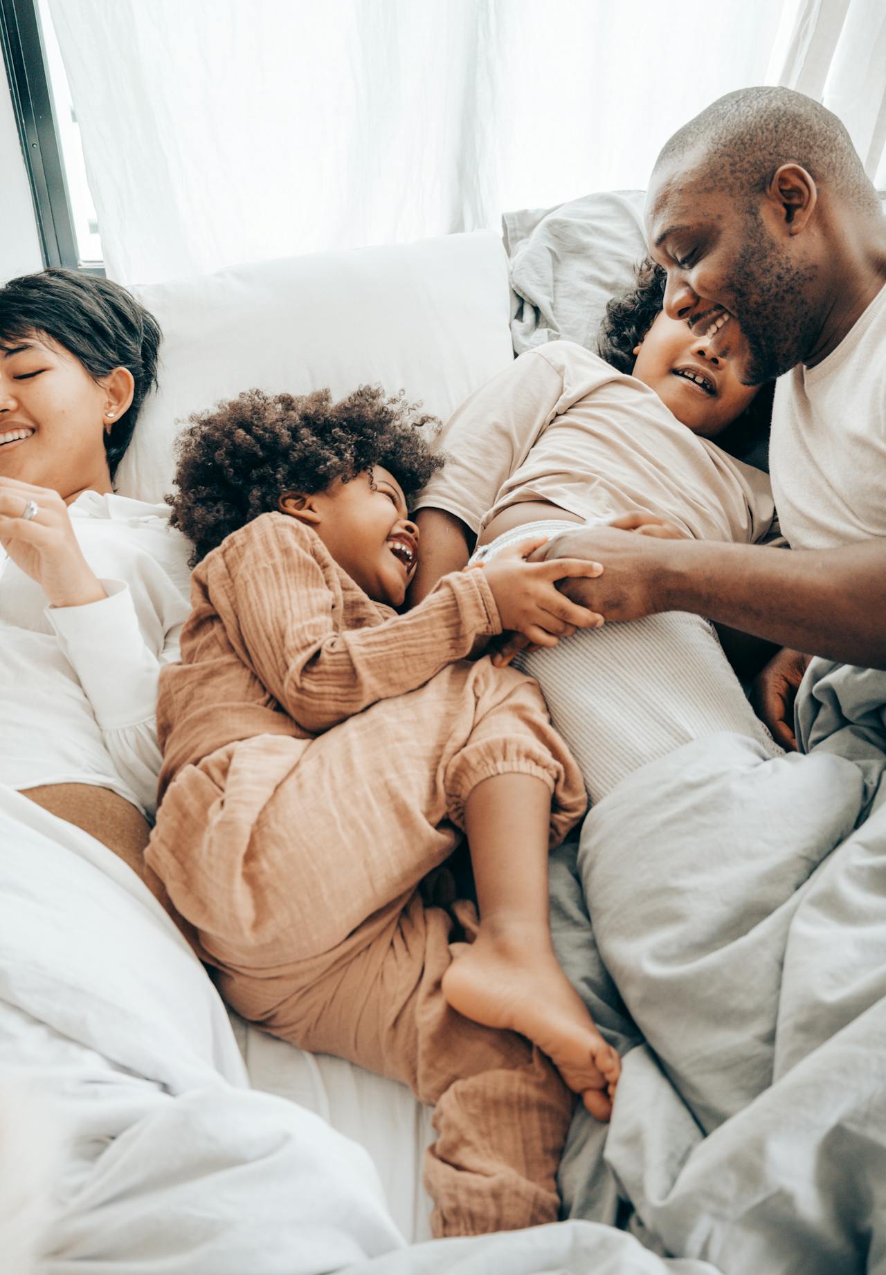 Image of a happy family playing and laughing together in bed, enjoying a loving and joyful moment.