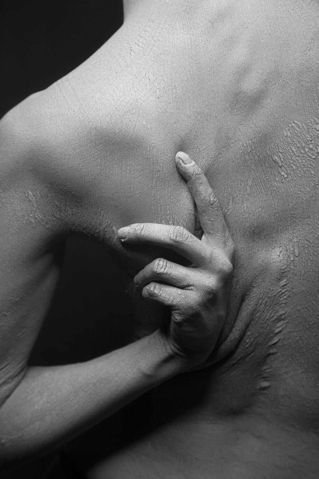 Black-and-white image of a woman's back with dry, cracked skin as they scratch an itchy area, showing how to relieve postpartum itching.