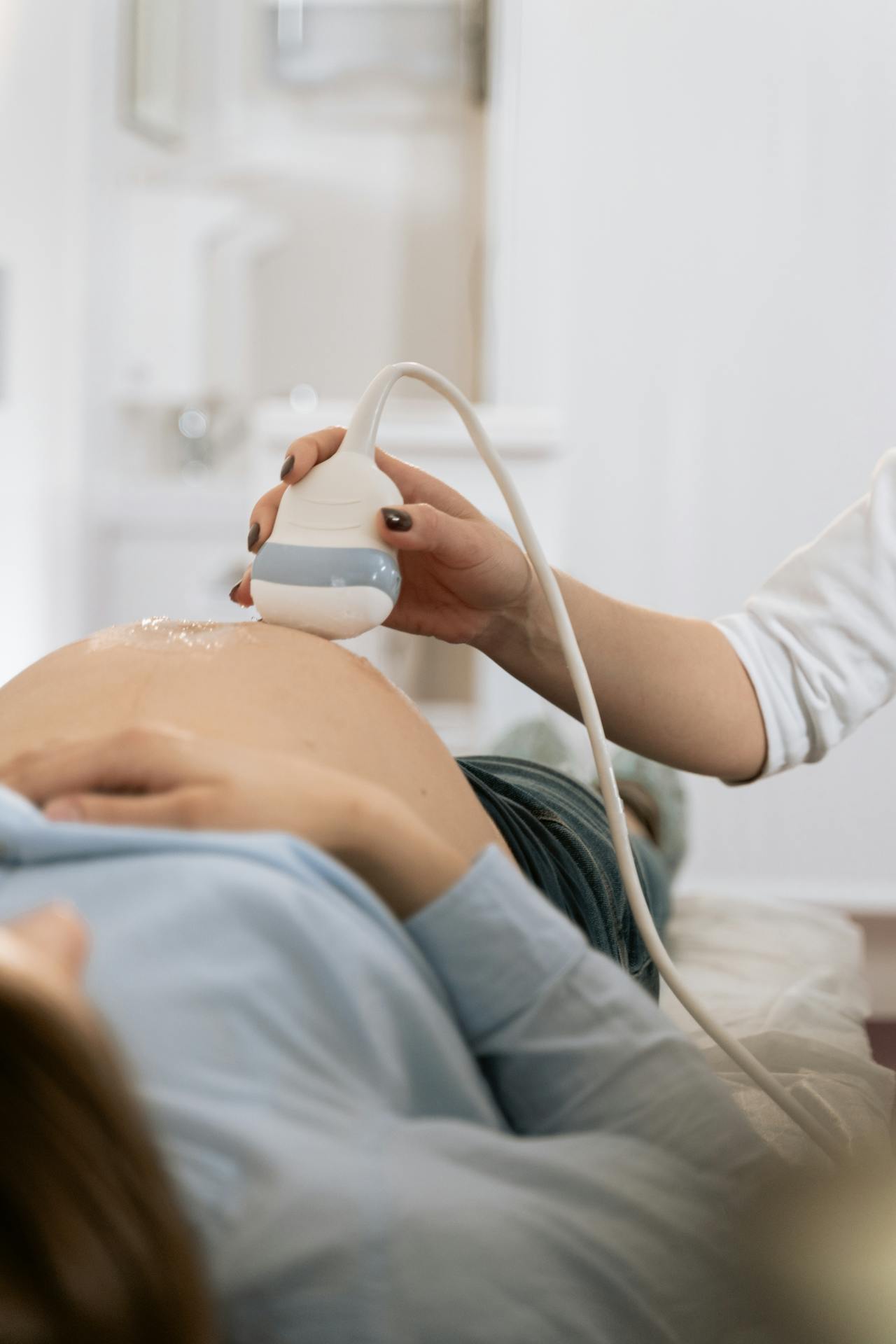 Close-up image of a of a medical professional performing an ultrasound on a pregnant woman's belly, showing how to tell the difference between prodromal labor and real labor.