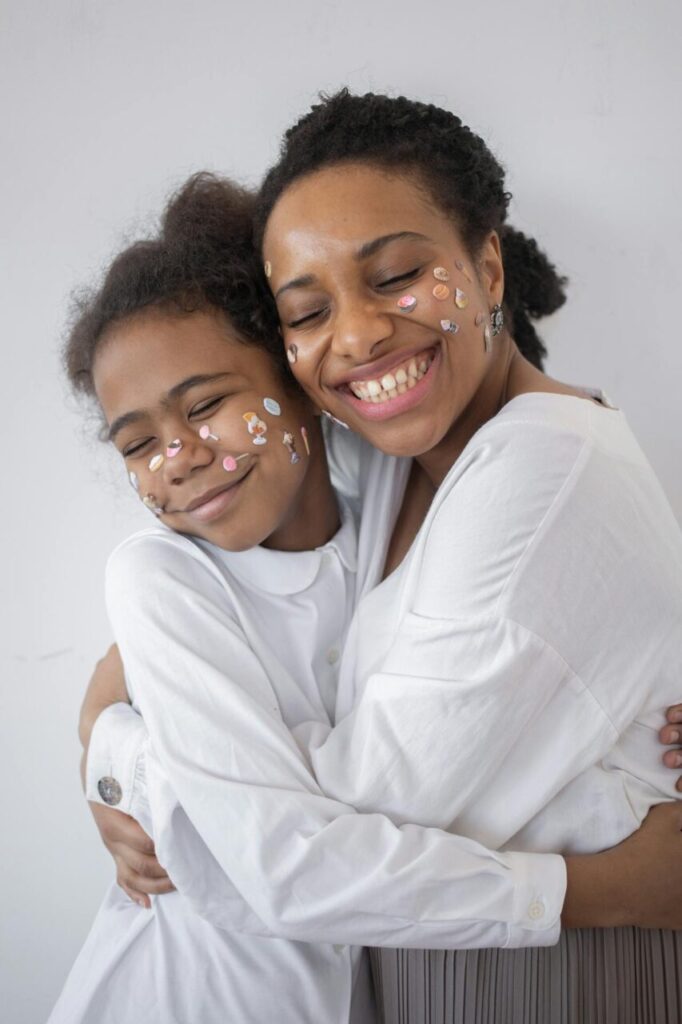 Image of a mother and daughter hugging with smiles, stickers on faces, both wearing white shirts, showing inspirational stay at home mom quotes.