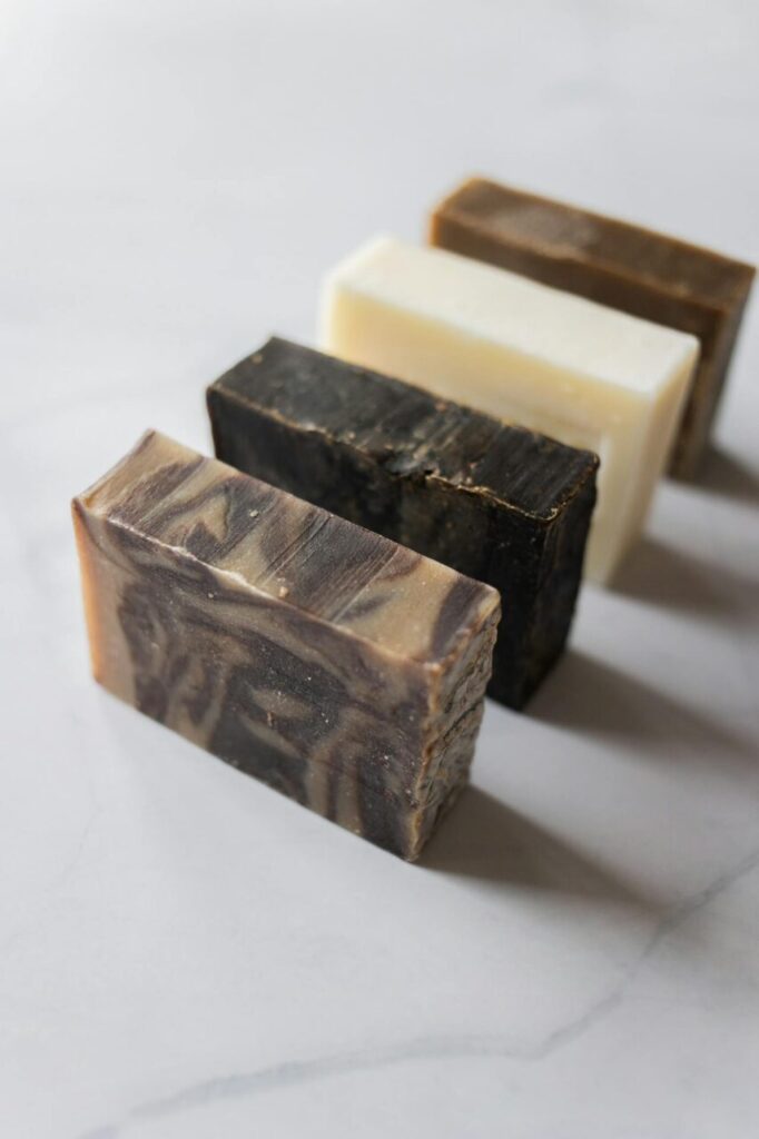 Image of a four handmade soap bars of different colors arranged diagonally on a white marble surface, representing what is antibacterial soap good for.