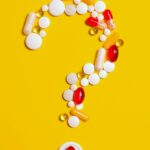 Image of assorted pills and capsules arranged in the shape of a question mark on a yellow background, showing is glutathione safe during pregnancy?