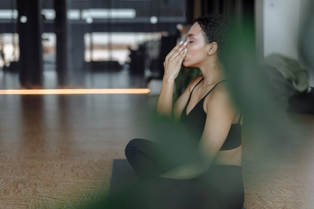 How to Stop Pelvic Floor Muscle Spasms? Image of a woman practicing yoga and breathing exercises indoors, sitting cross-legged in a calm, modern studio.