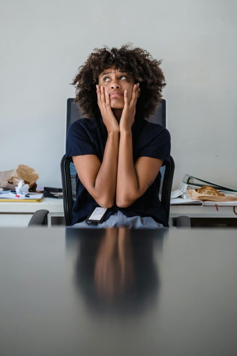 Image of a woman covering her ears looks stressed as multiple hands point fingers at her from all sides, showing what to do when you feel overwhelmed with life.