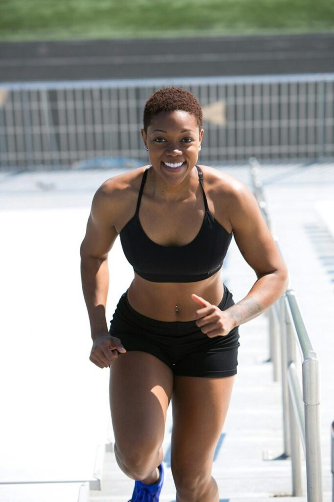Image of a smiling athletic woman in black sportswear running outdoors, showing strength and fitness, showing how to glow-up physically