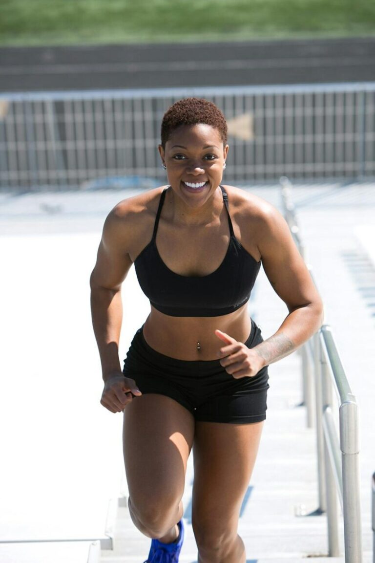 Image of a smiling athletic woman in black sportswear running outdoors, showing strength and fitness, showing how to glow-up physically