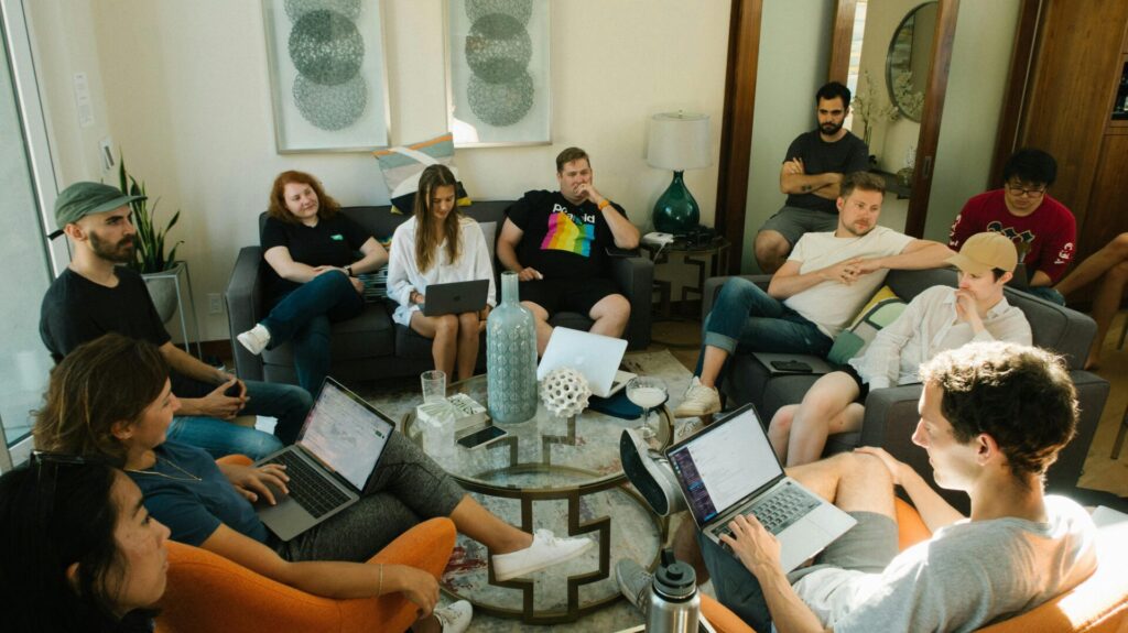 Image of a group of people sitting in a living room, collaborating with laptops during a casual team meeting, showing how to find Huntsville support groups.