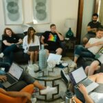 Image of a group of people sitting in a living room, collaborating with laptops during a casual team meeting, showing how to find Huntsville support groups.