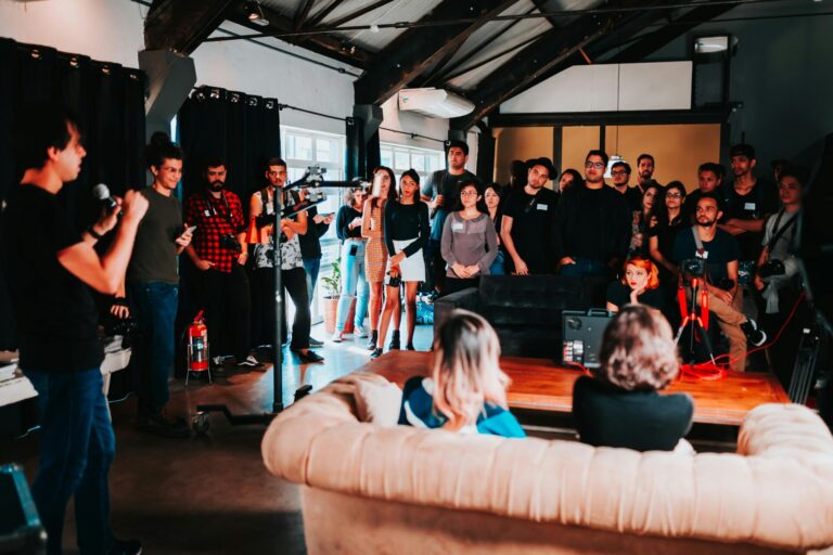 Image of a speaker presents to a diverse group of people gathered in an industrial-style event space, showing how huntsville moms are creating community to support each other.