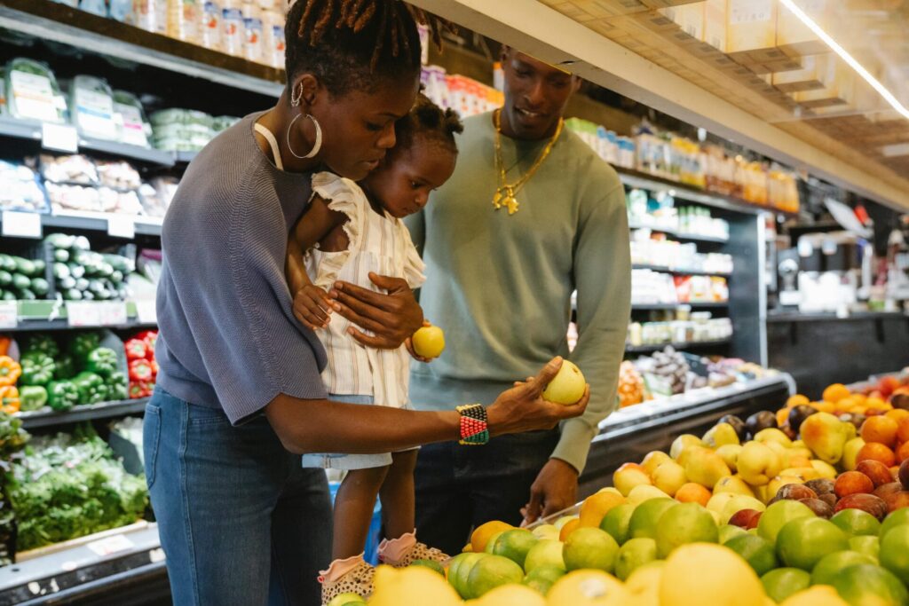Image of a black family shopping for fresh produce in a grocery store, holding apples while choosing fruits, showing Is Huntsville Alabama safe for black people.