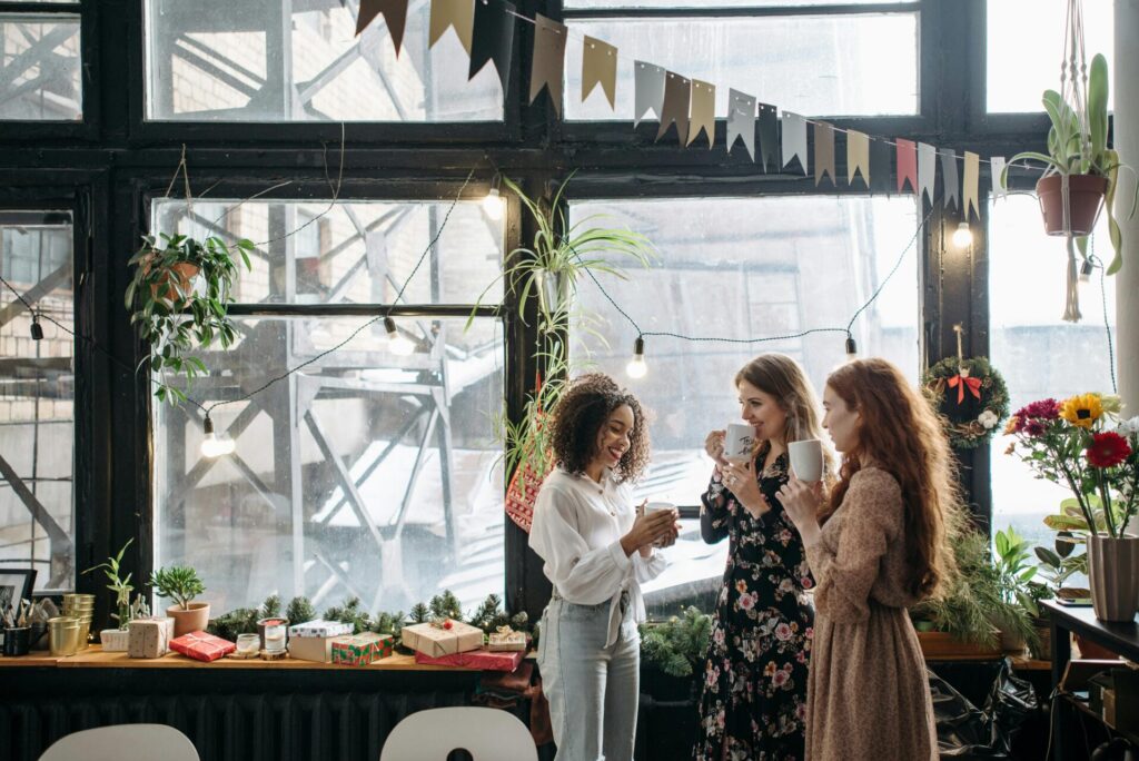Image of three women's standing in living room enjoying tea and gossips, with decorative background.